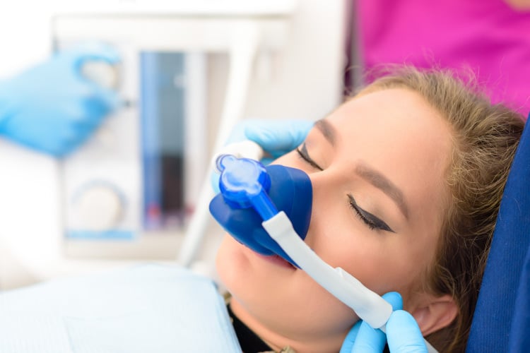 Woman with a mask over her nose inhaling nitrous oxide dental sedation