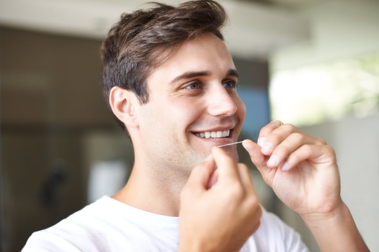 man flossing his teeth in katy, tx